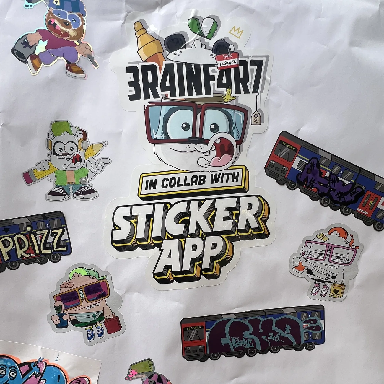 Væg dækket af håndfarvelagte konturskårne klistermærker fra Brainfart x StickerApp og etiketter med S8 World-toget med graffititags
