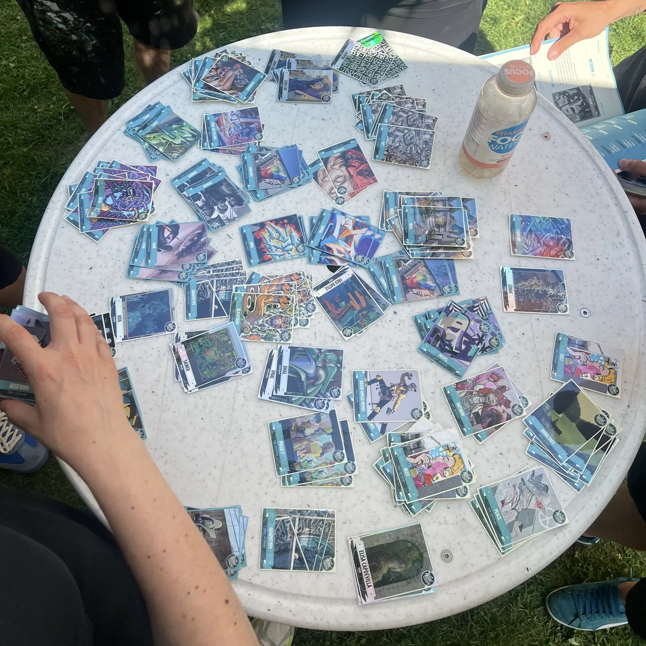 Festivalgæster udfylder blå klistermærkealbum med samlekort af klistermærker med gadekunst, spredt ud over et rundt bord