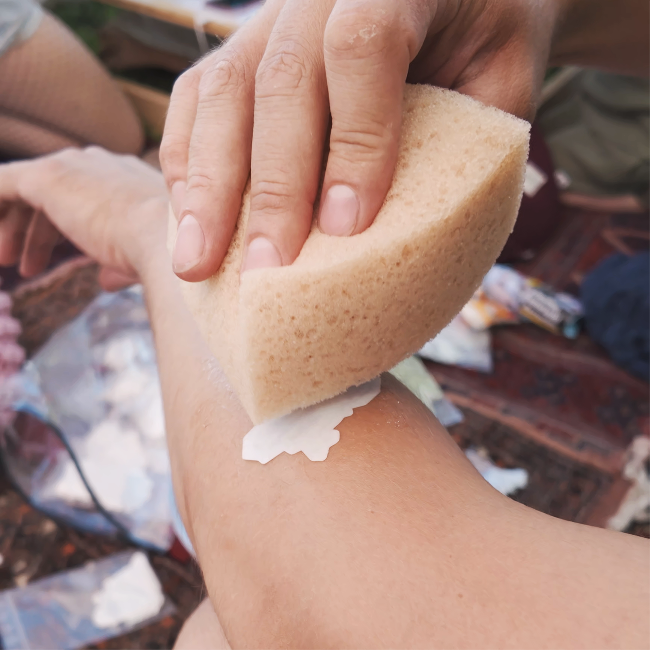 Die-cut temporaty tattoo in light and dark green, placed on an arm and patted with a sponge