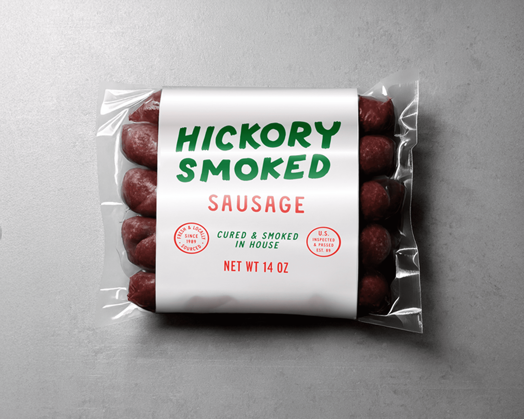 Label of hickory smoked sausages on a gray surface, featuring bold green and red text, weighing 14 oz.